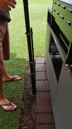 a person standing next to an oven in the grass with their feet on the ground