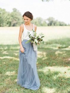 a woman standing in the grass holding a bouquet