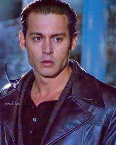 a close up of a person wearing a leather jacket and looking at the camera with a serious look on his face