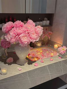 pink flowers in a vase on a table with candles and confetti around it