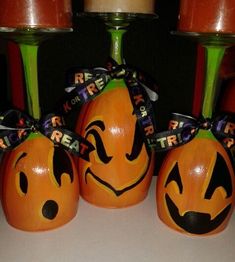 three pumpkins with faces painted on them are sitting next to each other in front of two candles