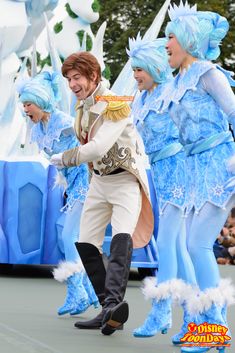 a group of people dressed in blue and white costumes, dancing on stage at an event