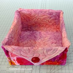 a pink and red bag sitting on top of a cutting board next to a ruler