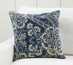 a blue and white pillow sitting on top of a white couch next to a wall