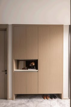 an empty room with wooden cabinets and shoes on the floor in front of it is a vase filled with flowers