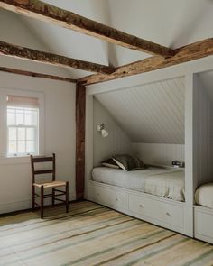 an attic bedroom with two beds and a chair next to the bed in the room