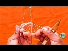 two hands are holding an ornament made out of wood and wire, with the string attached to it