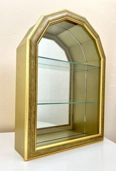 a gold shelf with a mirror on it and some shelves in front of the wall