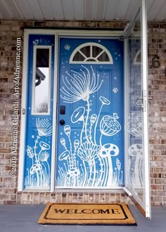 a welcome mat is placed in front of a blue door with white flowers and plants painted on it