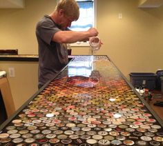 a man pouring water into a glass on top of a table covered in buttons and magnets