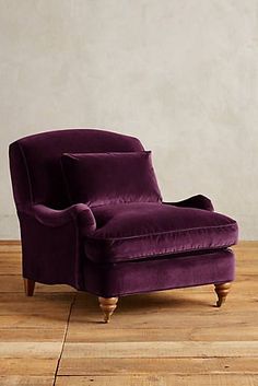 a purple chair sitting on top of a hard wood floor next to a white wall