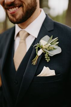 a man wearing a suit and tie with a boutonniere on his lapel