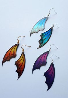 three different colored wings hanging from earrings