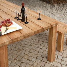 a wooden table topped with a plate of cheese and two wine glasses on top of it