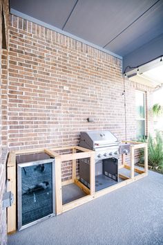 an outdoor bbq grill built into the side of a brick wall with doors open