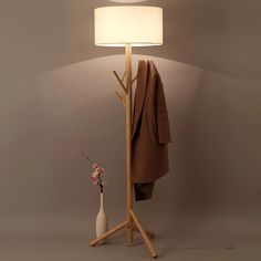 a coat rack with a white vase next to it and a lamp on the floor