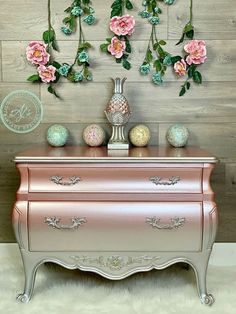 a pink dresser with flowers hanging from it's sides