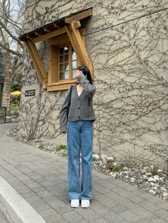 a woman standing in front of a building with a window on it's side