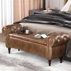 a bed with a brown leather bench in front of it