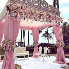 an outdoor wedding setup with pink drapes and flowers