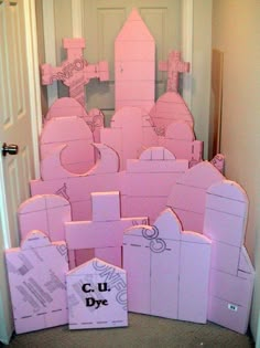 pink castle made out of cardboard boxes sitting in front of a door with the words cut - up written on it