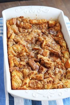 a casserole dish filled with bread and other toppings on a blue and white towel