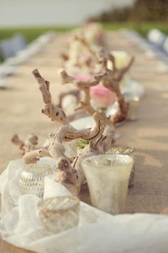 two vases sitting on top of a table covered in flowers and candlesticks