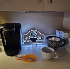 there is a coffee maker and cups on the counter