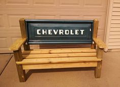 a wooden bench sitting in front of a garage with the word chevrolet written on it