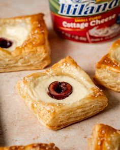 small pastries with cream cheese and cherries on them next to a can of milk