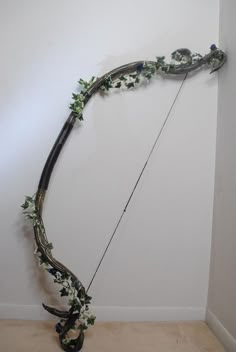 a bow that has been decorated with flowers and vines on the side of a wall