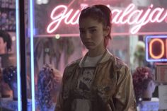 a woman standing in front of a neon sign