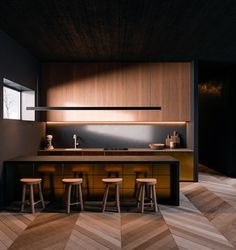 an image of a kitchen setting with stools in the middle and wood flooring