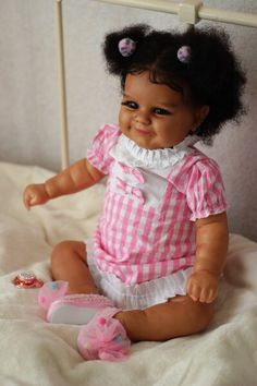 a baby doll sitting on top of a bed