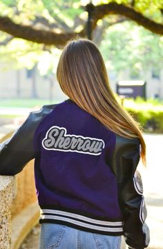 the back of a woman wearing a purple and black leather jacket with sherpan written on it