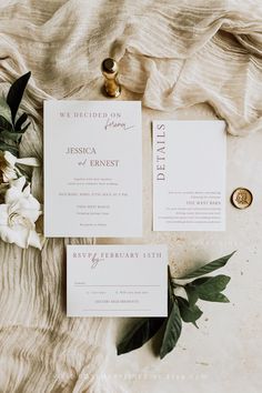 the wedding stationery is laid out on top of a table with flowers and greenery