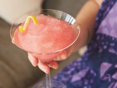 a close up of a person holding a wine glass with a pink drink in it