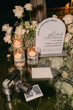 a table with flowers, candles and a sign on it that says guest book in front of them