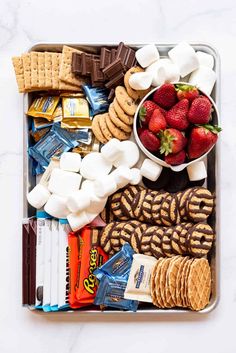 a tray filled with cookies, marshmallows, strawberries and other snacks