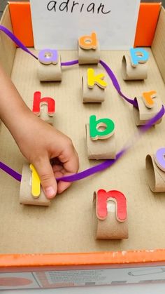 a child's hand is playing with wooden letters