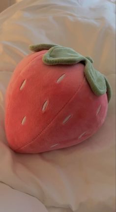 a strawberry pillow sitting on top of a bed