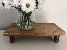 a glass vase with white flowers sitting on a wooden table