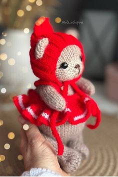 a small teddy bear wearing a red and white knitted outfit sitting on top of a table