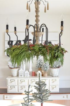 a chandelier with christmas decorations and greenery hanging from it's arms