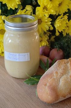 a jar of mustard next to bread and flowers