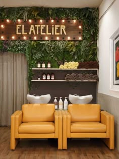 two yellow chairs sitting next to each other in front of a wall covered with plants