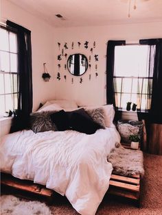 two pictures of a bed with white sheets and black pillows, one has a mirror on the wall