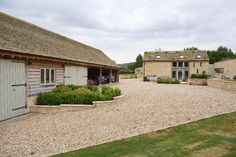 a stone building with two garages and gravel driveway