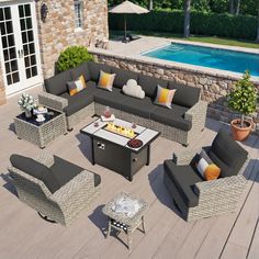 an outdoor living room with grey wicker furniture next to a pool and stone wall