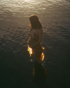 a woman standing in the water with her back to the camera